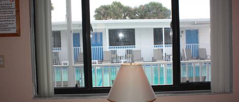 Habitación con vista a una piscina y un cartel que detalla las normas para visitantes y los precios.