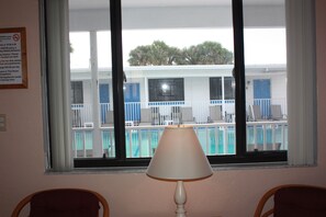A room with a view of a pool and a sign detailing visitor policy and fees. - iBeach Resort (Treasure Island)