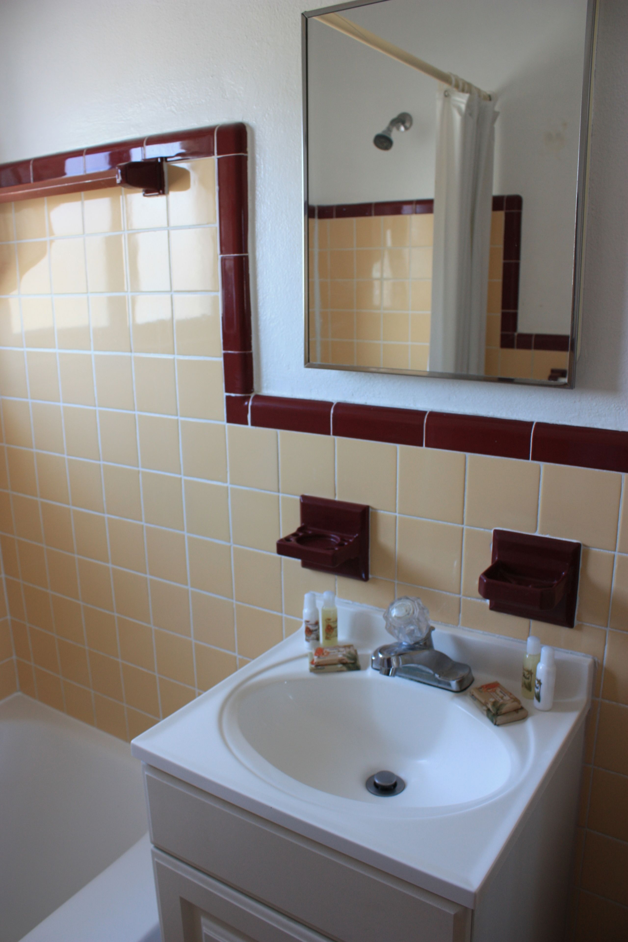 A bathroom with a white sink, mirror, and tiled walls.