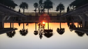 A serene lakeside view with a sunset reflected on the water, surrounded by trees and a wooden deck. - iBeach Resort (Treasure Island)