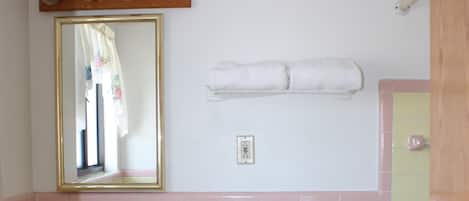 Un baño con inodoro, lavamanos, espejo y toallero.
