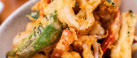 A bowl of fried seafood, including shrimp and squid, with a green chili visible.