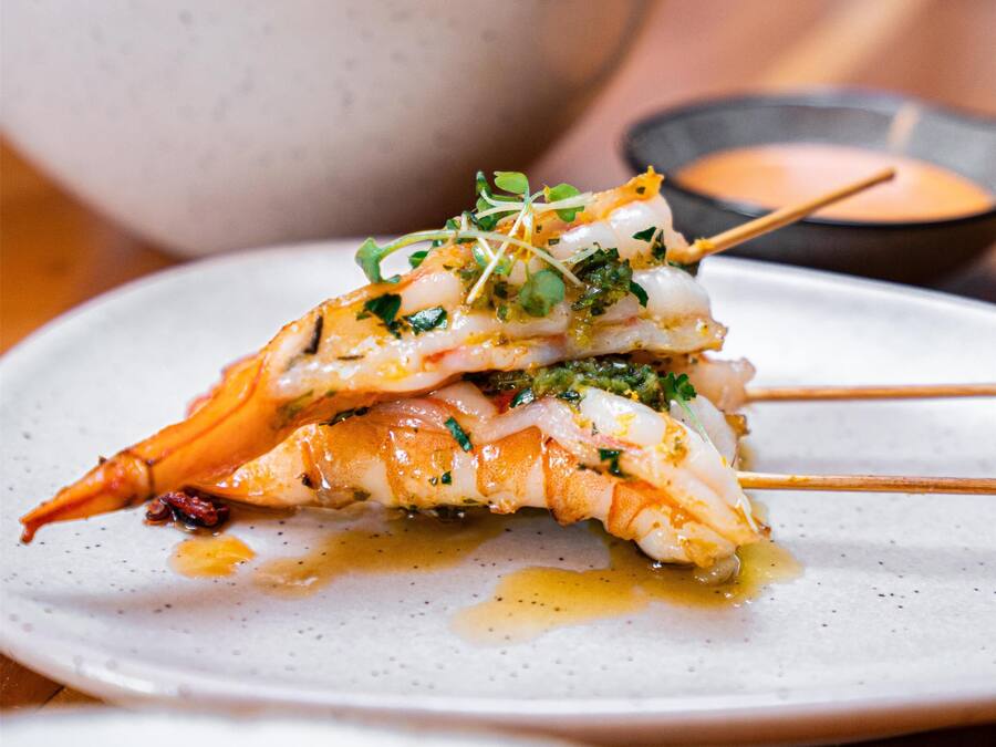 A plate of food with a seafood dish, a bowl in the background, and a small dish with sauce.