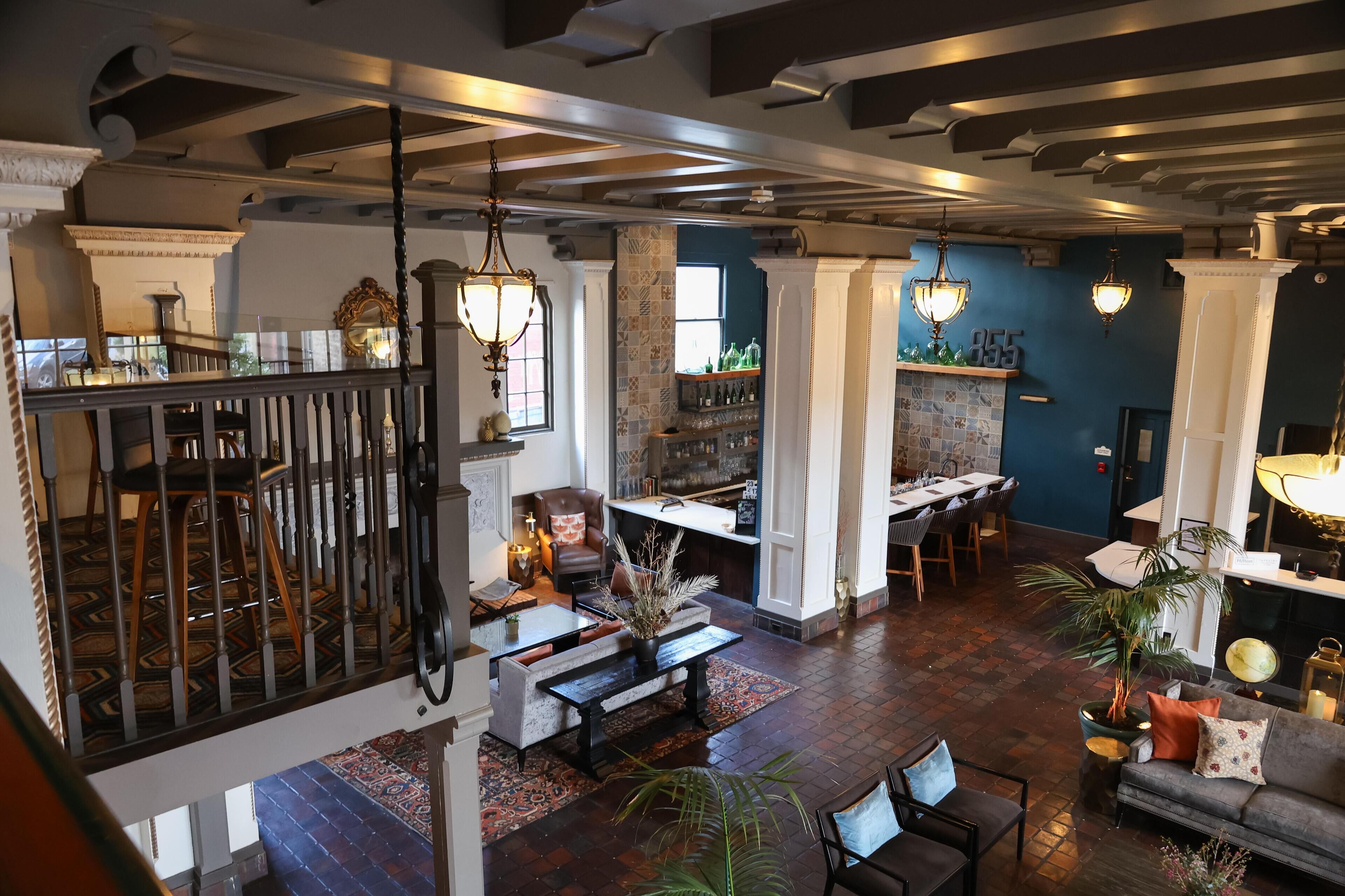 A spacious interior with a high ceiling, exposed beams, and a mix of seating areas including a bar and a dining area.