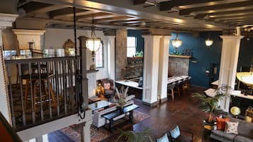 A spacious interior with a high ceiling, exposed beams, and a mix of seating areas including a bar and a dining area.