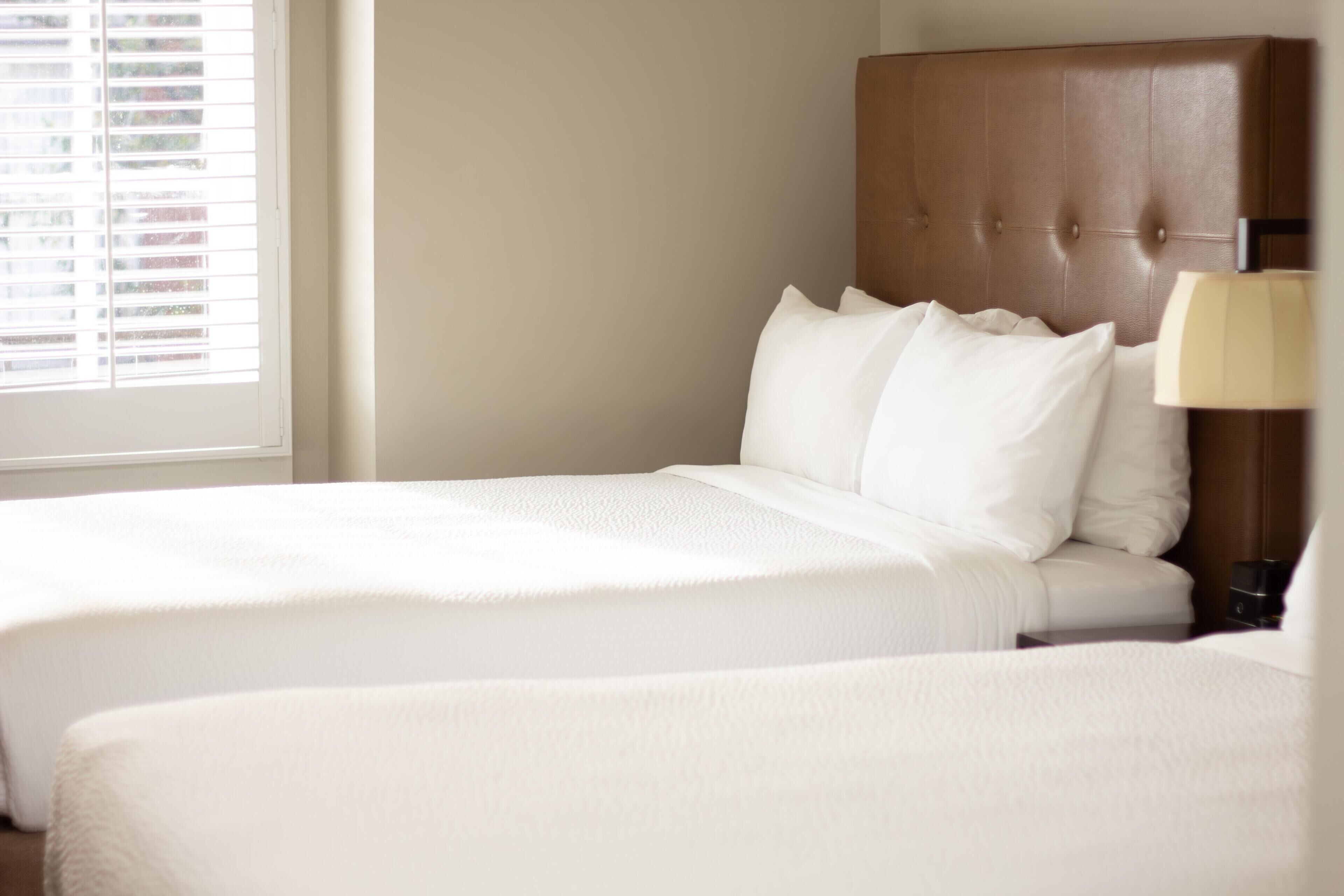 Una habitación de hotel con una cama grande, un cabecero y una ventana con persianas.