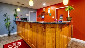 A reception area with a wooden counter, a potted plant, and a red doormat.