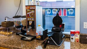 A kitchen counter with a waffle maker, a coffee machine, a cereal dispenser, and a coffee maker.
