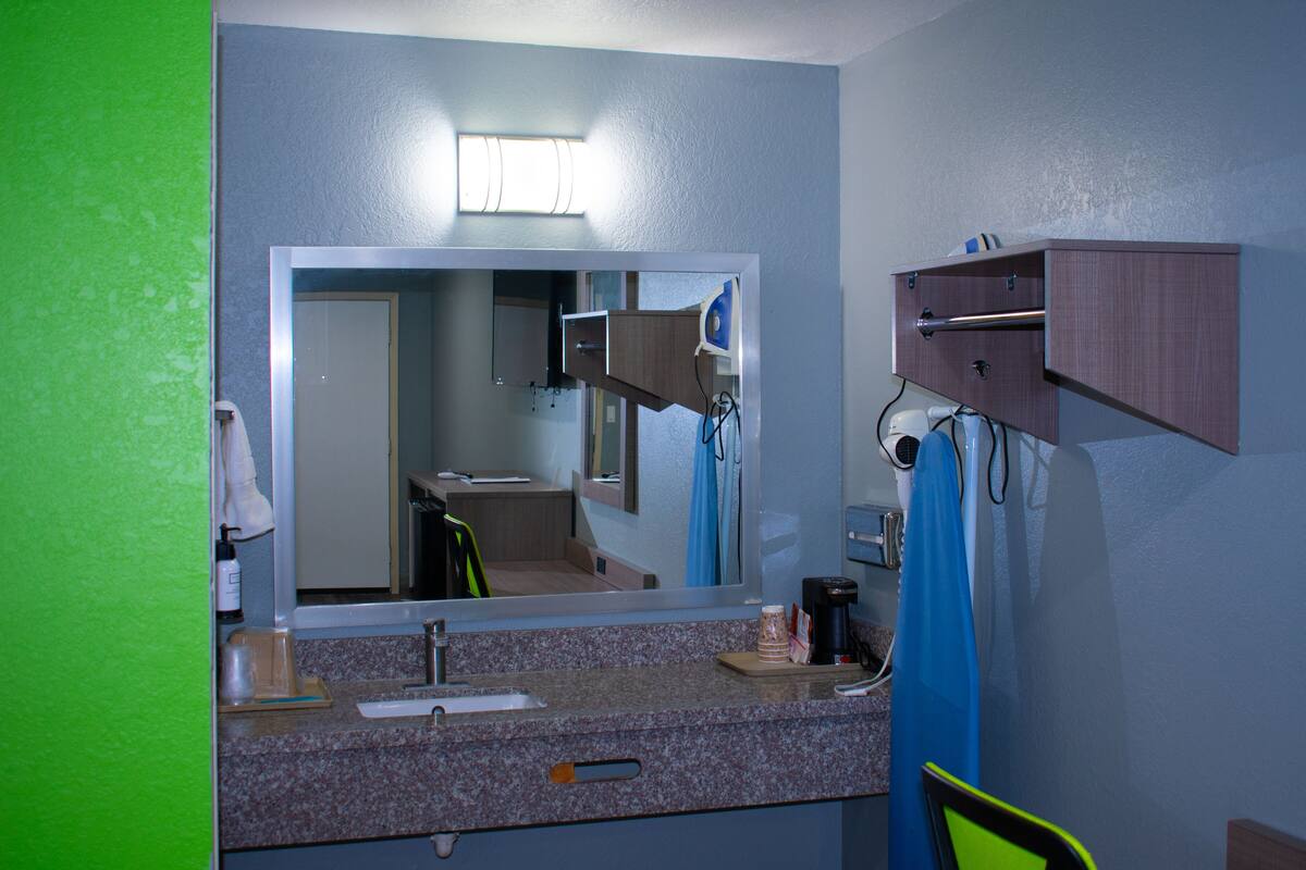 Um banheiro com um espelho grande, pia, porta-toalhas e armário.