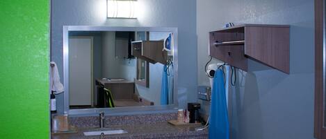 Un bagno con un grande specchio, un lavandino, un portasciuga e un armadietto.