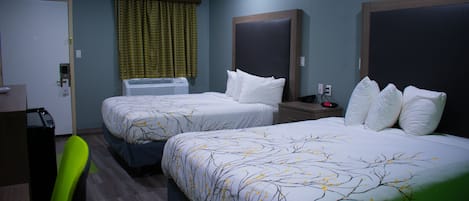 Une chambre d’hôtel avec deux lits, un bureau, une chaise, un appareil de climatisation et une horloge.