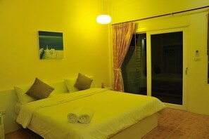 A hotel room with a bed, pillows, a painting on the wall, a curtain, and a sliding door. - Boutique Guesthouse by Clearhouse (Kamala)