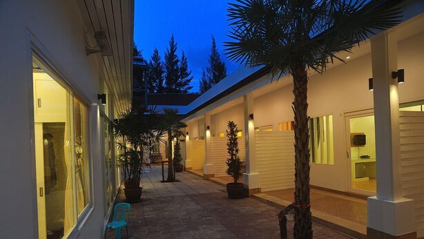A modern house with a covered patio, potted plants, and a blue chair. - Boutique Guesthouse by Clearhouse (Kamala)