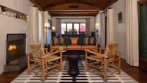 Un salon chaleureux avec une cheminée, un canapé et deux fauteuils en osier.