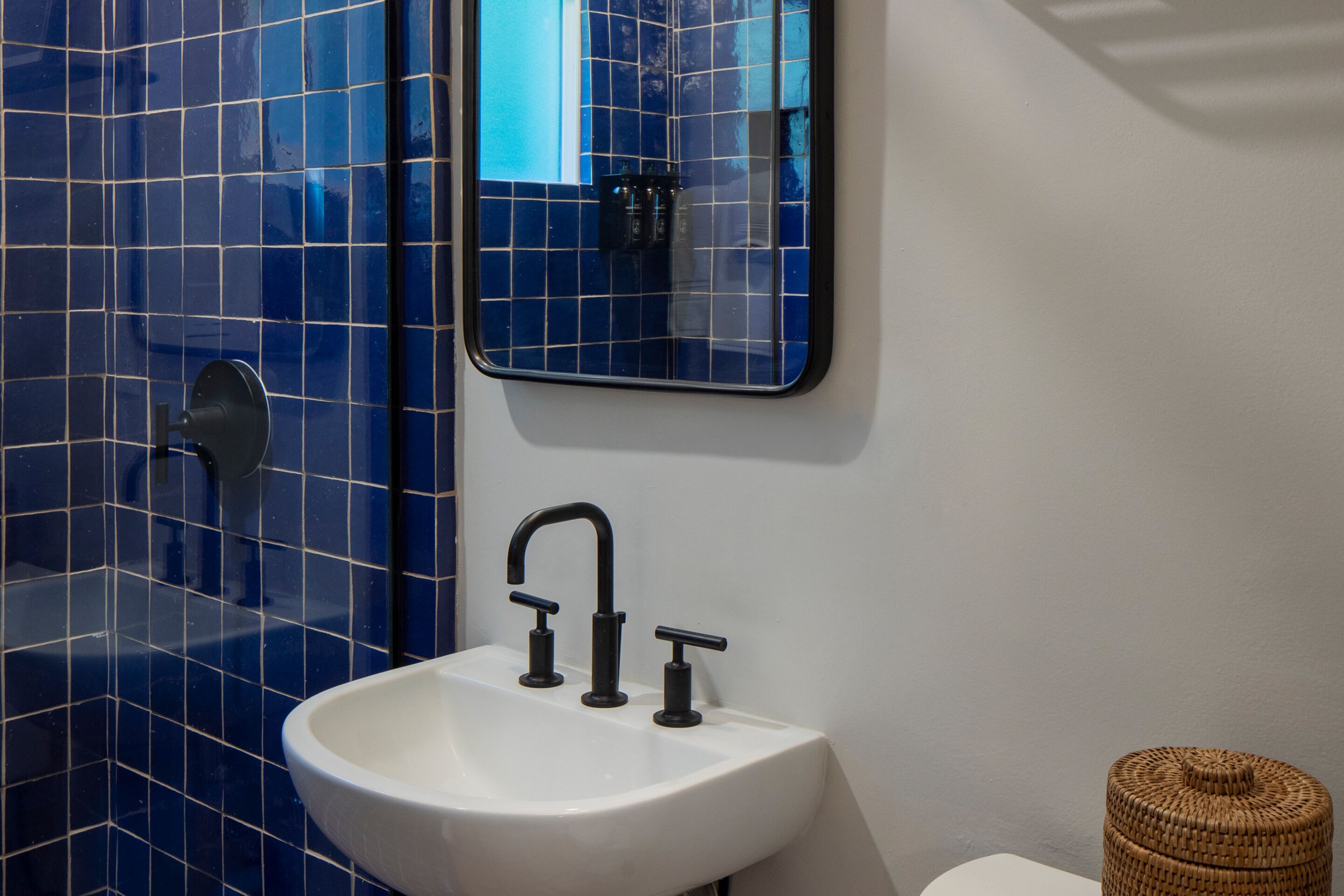 A bathroom with a white sink, black faucet, and blue tiled walls.