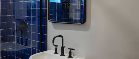A bathroom with a white sink, black faucet, and blue tiled walls.