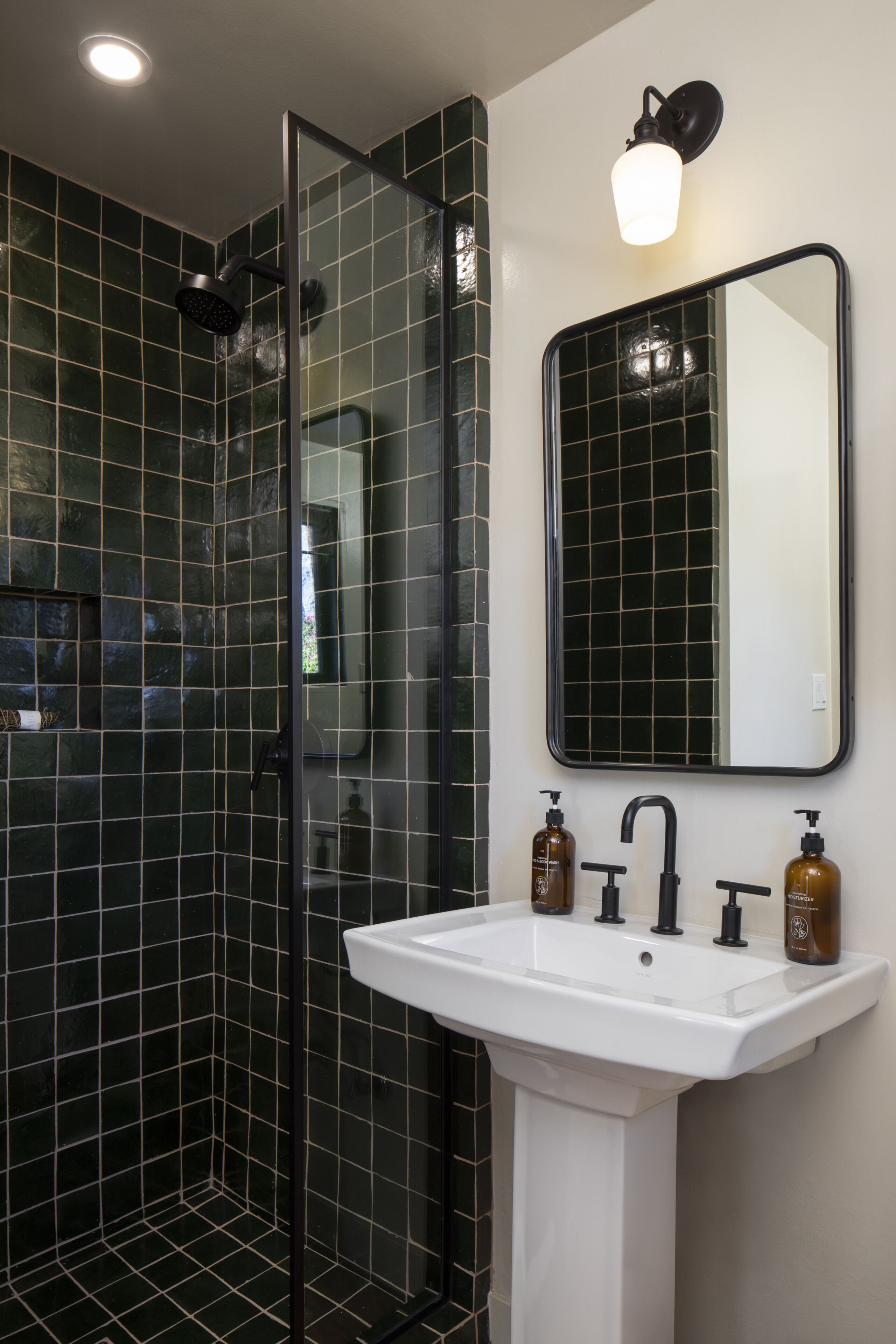 Een badkamer met een douchecabine van glas, een wit wastafelmeubel en een spiegel erboven.