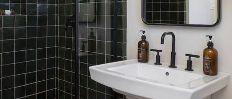 Een badkamer met een douchecabine van glas, een wit wastafelmeubel en een spiegel erboven.