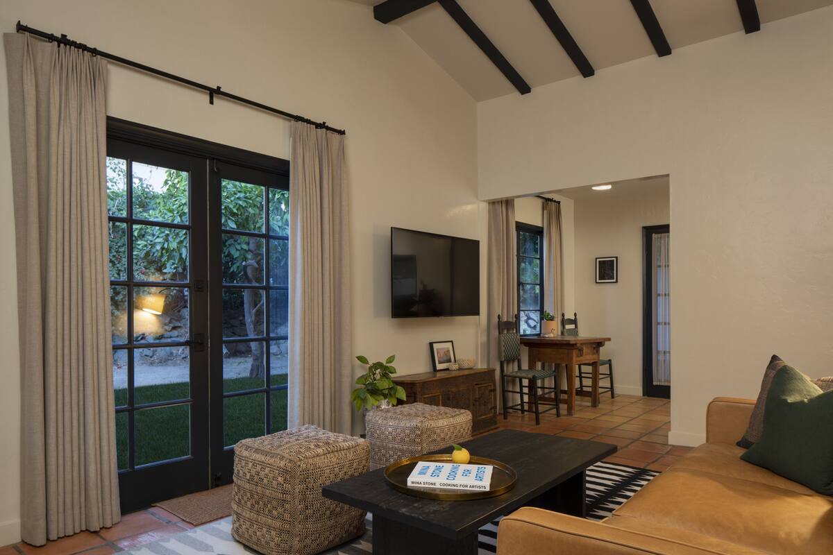A living room with a sofa, a coffee table, and a television. There is a dining area with a table and chairs.