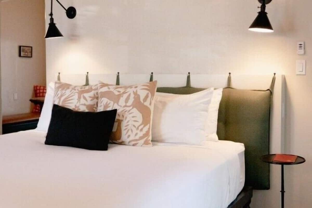 A neatly made bed with patterned pillows, a headboard, and two bedside lamps.