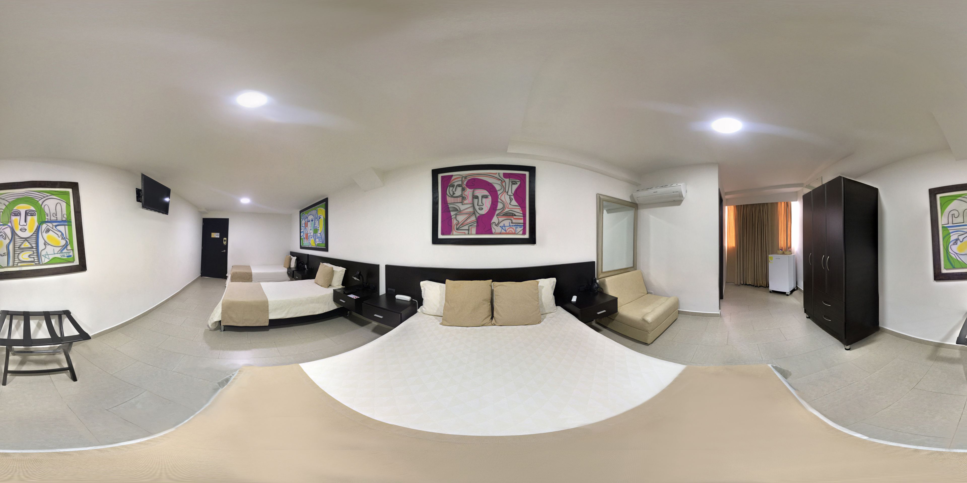 Une chambre d’hôtel moderne avec un lit aux lignes courbes, deux tables de chevet, une armoire et des œuvres d’art accrochées aux murs.