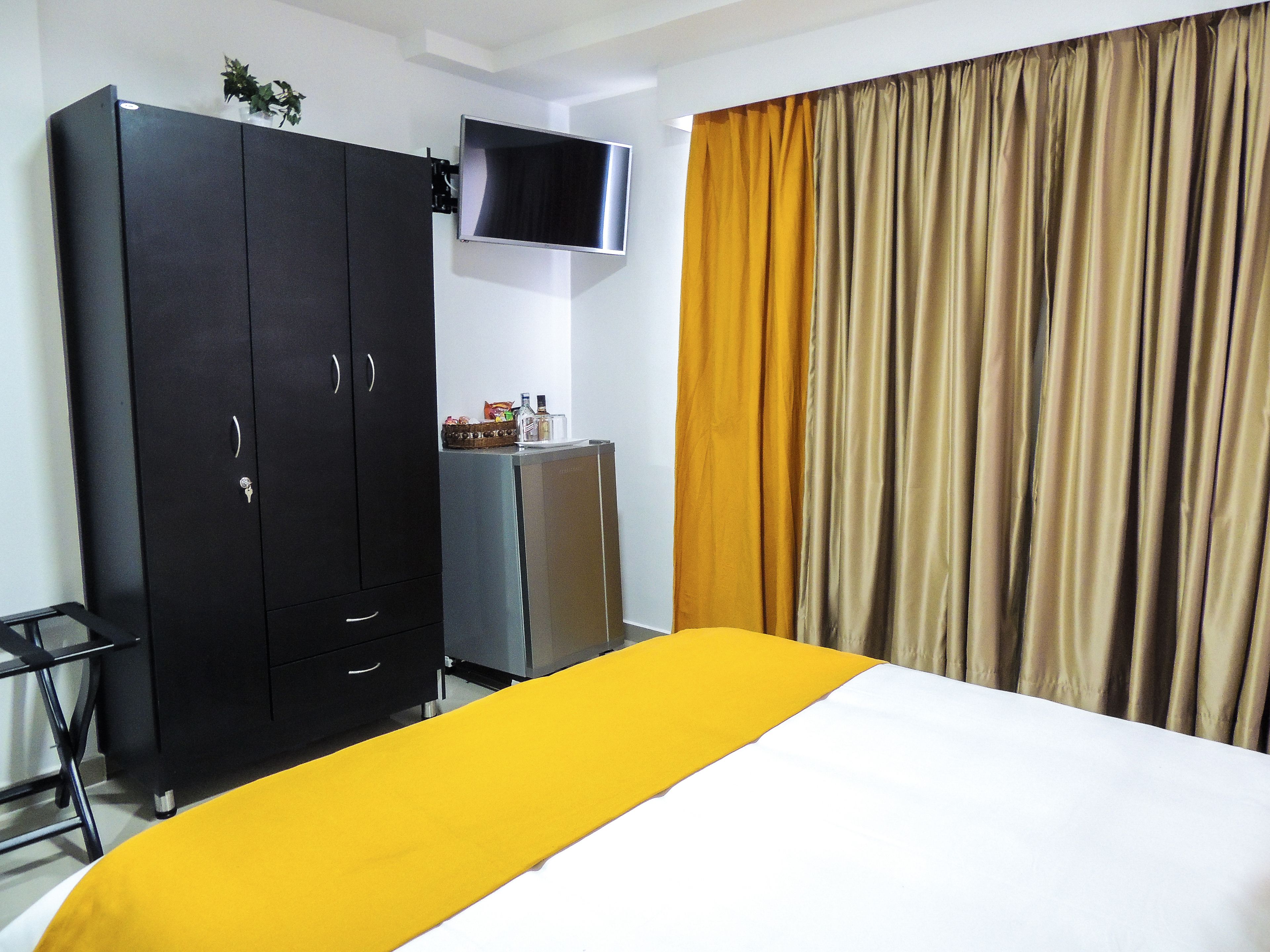 Una habitación de hotel con cama, armario, televisión y cortinas.
