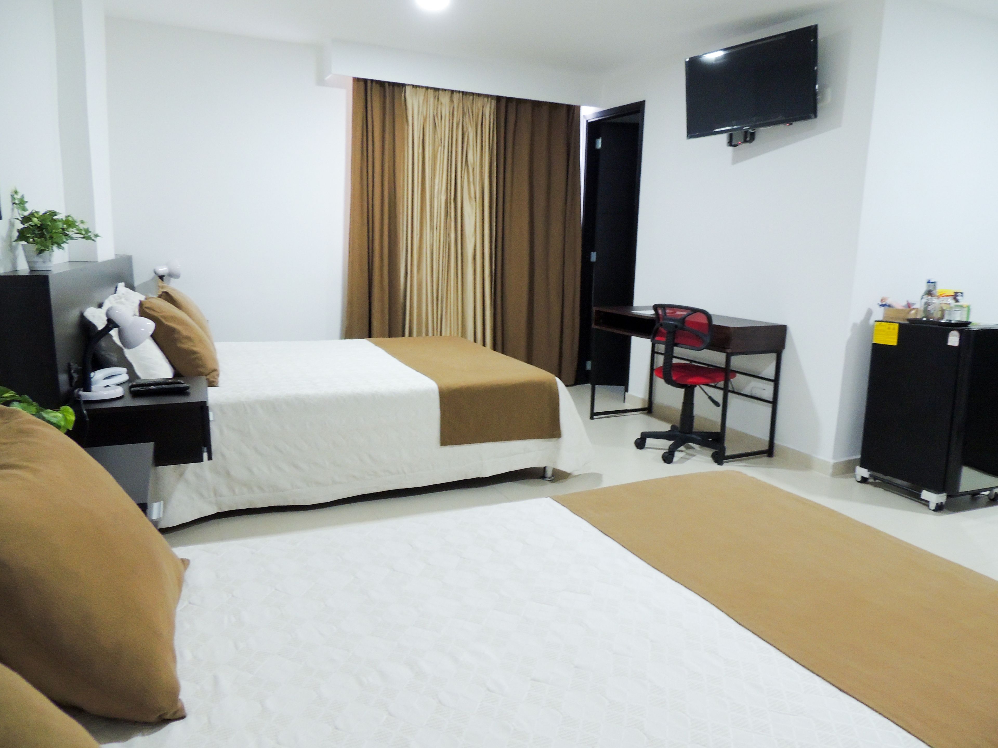 Ein Hotelzimmer mit Bett, Schreibtisch, Stuhl, Fernseher und Kleiderschrank.