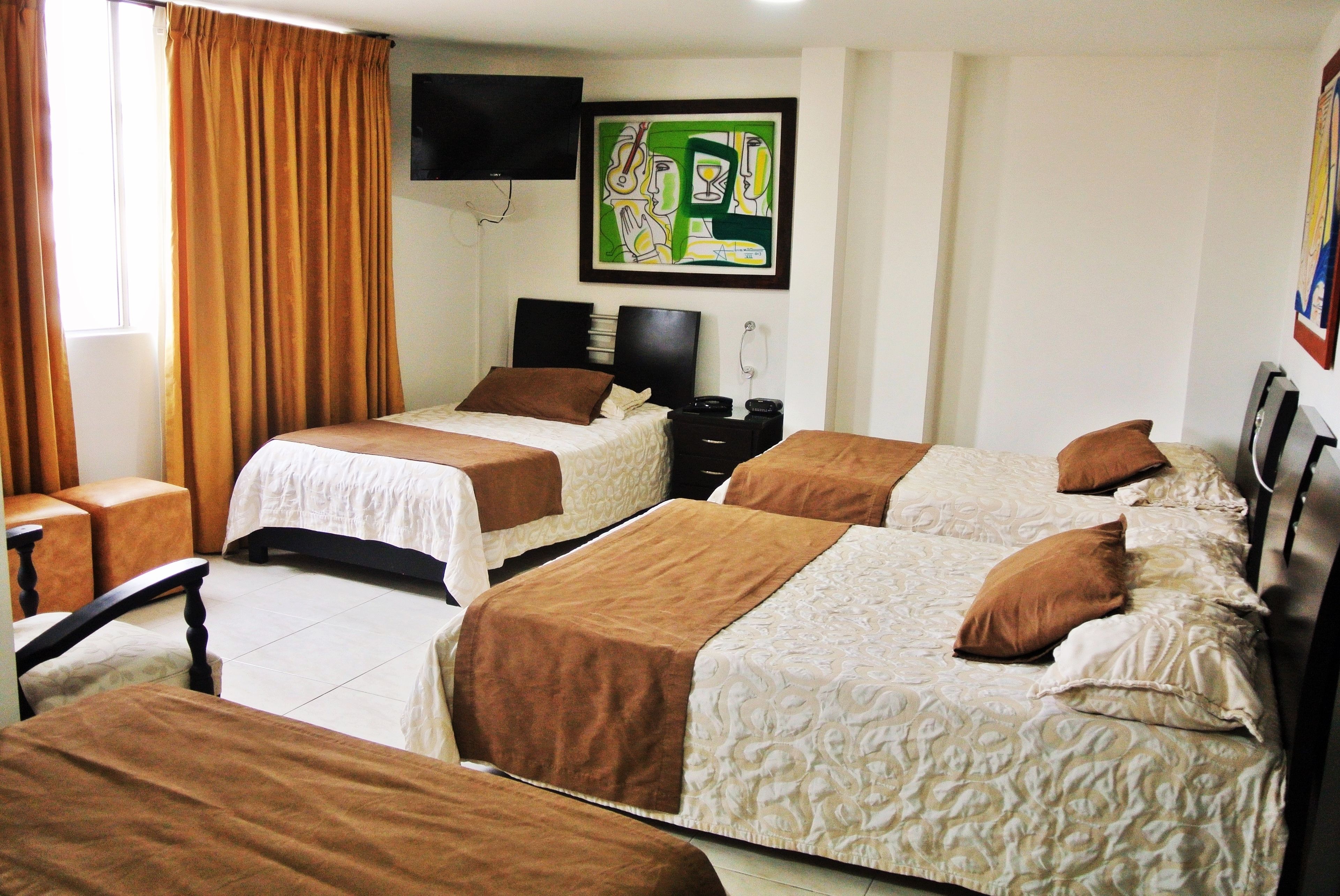 Habitación de hotel con dos camas, cabeceros marrones y un televisor de pantalla plana montado en la pared.
