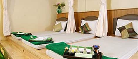 Une chambre avec deux lits, chacun doté d’un baldaquin, d’une tête de lit en bois et d’une couverture verte. Un plateau contenant des articles de toilette est posé sur le sol, entre les deux lits.