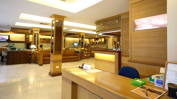 Zona de recepción de un hotel con un mostrador de madera, un letrero de recepción, un televisor y un acuario.