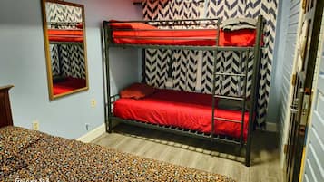 A bunk bed room with a mirror, patterned curtains, and a patterned bedspread.
