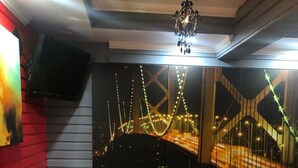 Un área de lounge moderna con sofás rojos, un sofá de cuero negro y un amplio ventanal que muestra un paisaje urbano con puentes iluminados.