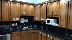 Una cocina con armarios de madera, encimera negra, microondas y estufa.