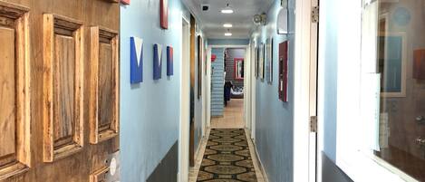 A hallway with wooden doors, a patterned carpet, and a sign indicating visitor restrictions.