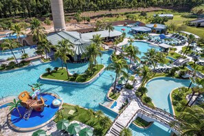 Ein Resort mit mehreren Schwimmbecken, Palmen und einer Wasserrutsche.