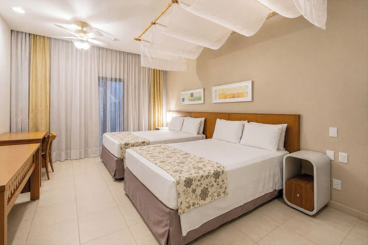A hotel room with two beds, a desk, and a small cabinet.