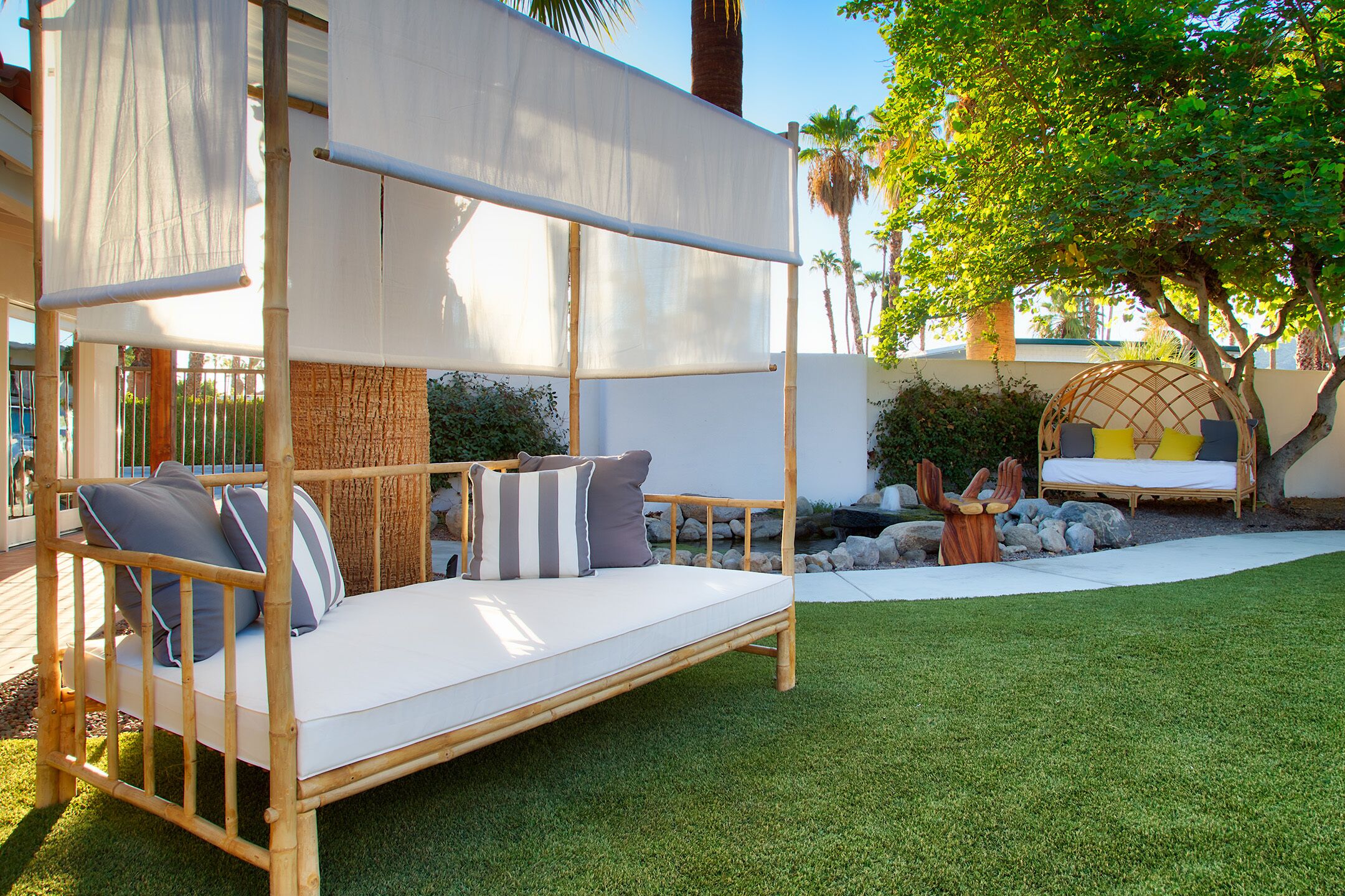 A hammock-style seating area with cushions, a white wall, and a tree.