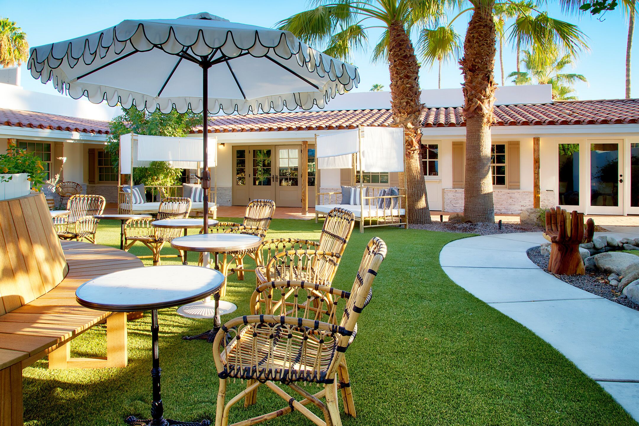 An outdoor patio area with wicker furniture, a white umbrella, and a well-maintained lawn.