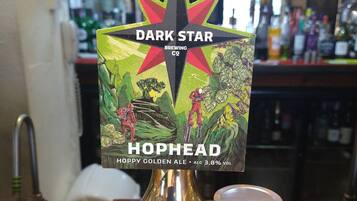 Un grifo con la etiqueta 'Dark Star Hophead Hoppy Golden Ale' y un vaso de cerveza a su lado.