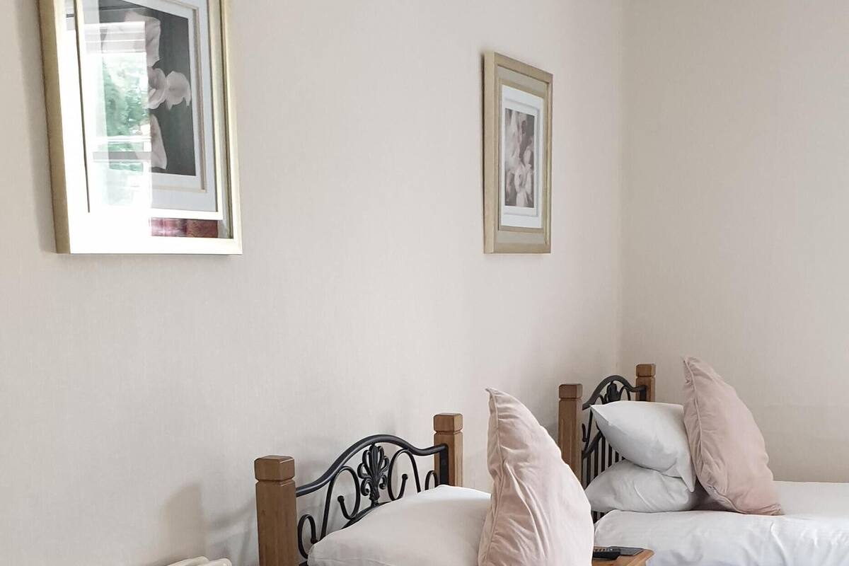 Un dormitorio con una cama, dos cuadros en la pared y un radiador.