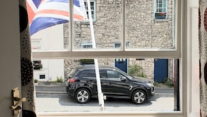 A view through a window with a stone building and a car parked outside.