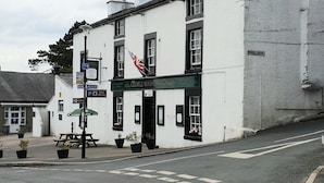 A white building with a black door and windows, a flag, and a sign that reads "George Washington."