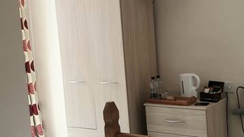 Een slaapkamer met een bed, een houten hoofdbord, een dressoir met spiegel, een aan de muur bevestigde televisie en een kledingkast.