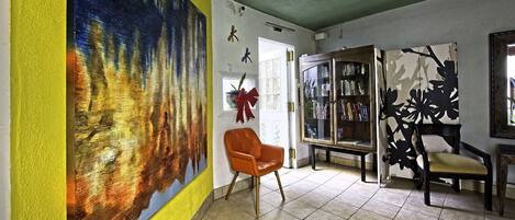 Une pièce avec un grand tableau abstrait, une bibliothèque et un fauteuil.