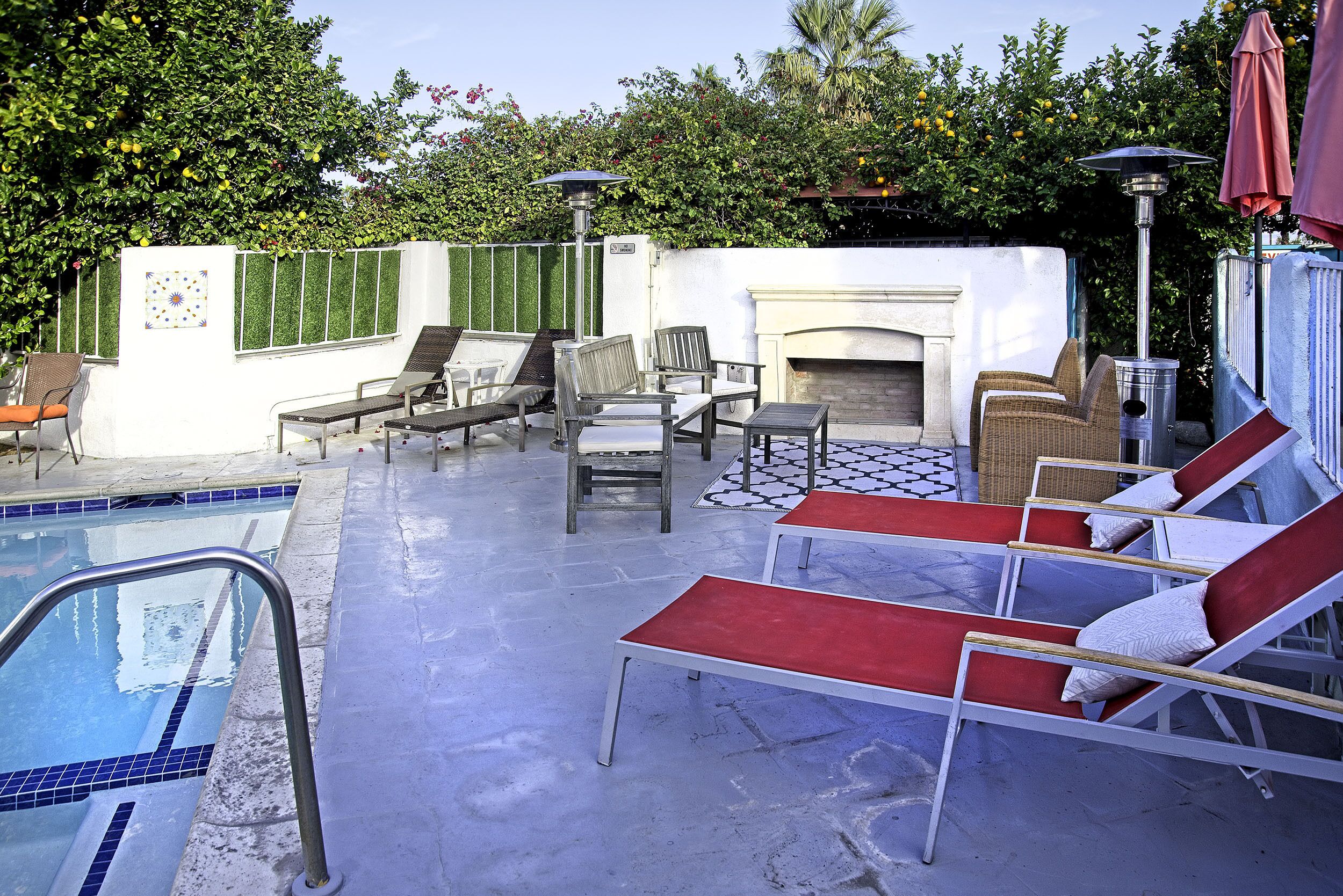 A poolside area with lounge chairs, a fire pit, and a tiled deck.