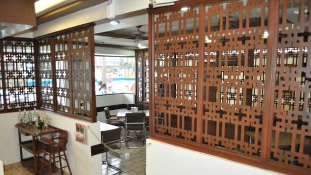 A traditional room with wooden lattice partitions, a dining area with chairs and a table, and a small bar area with bottles. - Hotel 5a Avenida (Monterrey)