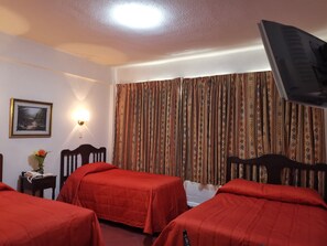 A hotel room with two beds, a TV, a lamp, a framed picture, and a curtain. - Hotel 5a Avenida (Monterrey)
