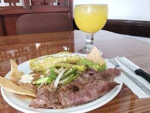 A plate of food including steak, vegetables, and a glass of orange juice. - Hotel 5a Avenida (Monterrey)