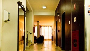 Un pasillo de hotel con suelo de baldosas, una escalera y taquillas a la derecha.