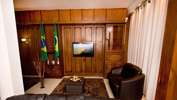 Una sala de estar con un sofá de cuero, un televisor y dos banderas en la pared.